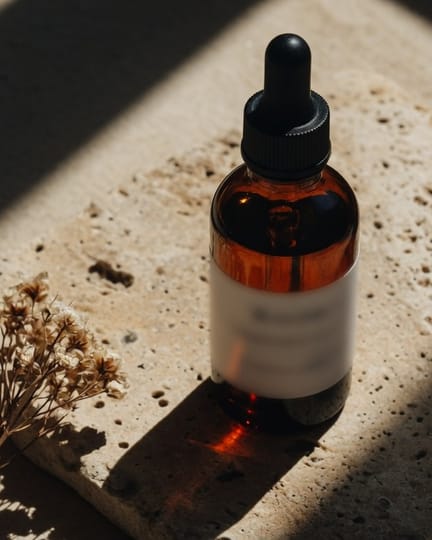 An amber serum bottle on a stone slab in hard sunlight